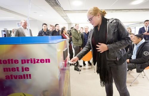 een studente haalt haar tegoedbonnetje uit de interactieve afvalbak, op de achtergrond zitten meerdere  andere studenten