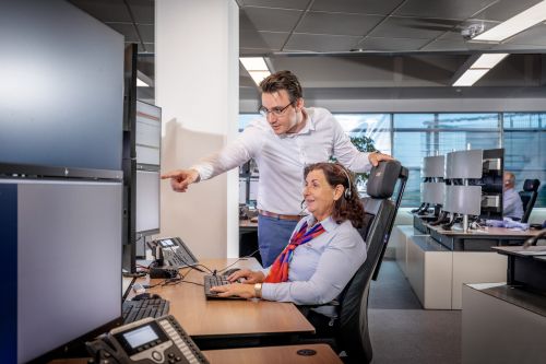 Man staat naast vrouwelijke Trigion collega die haar ondersteunt in haar werk.