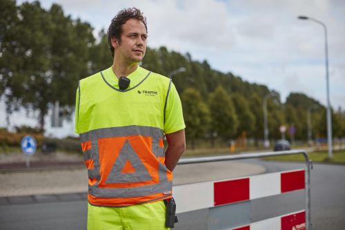 verkeersregelaar in geel pak met handen op de rug