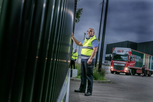 Beveiliger controleert samen met een collega het hekwerk op een bedrijventerrein