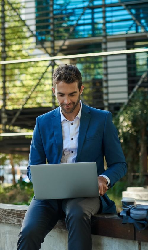 Adviseur vastgoedmanagement achter laptop op de stoep van een gebouw