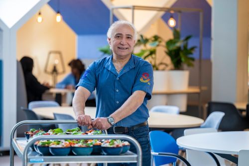 chef poseert lachend met rolkar vol lekkers