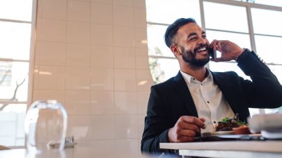 Lachende man aan het telefoneren met een bord met eten voor zich