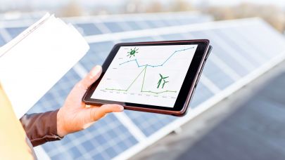 Facilitair medewerker op dak met zonnepanelen waar tablet rendement weergeeft