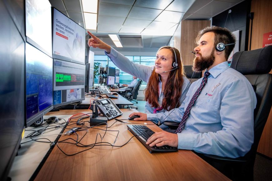 Twee centralisten bekijken de inkomende meldingen op het beeldscherm op de AlarmServiceCentrale.