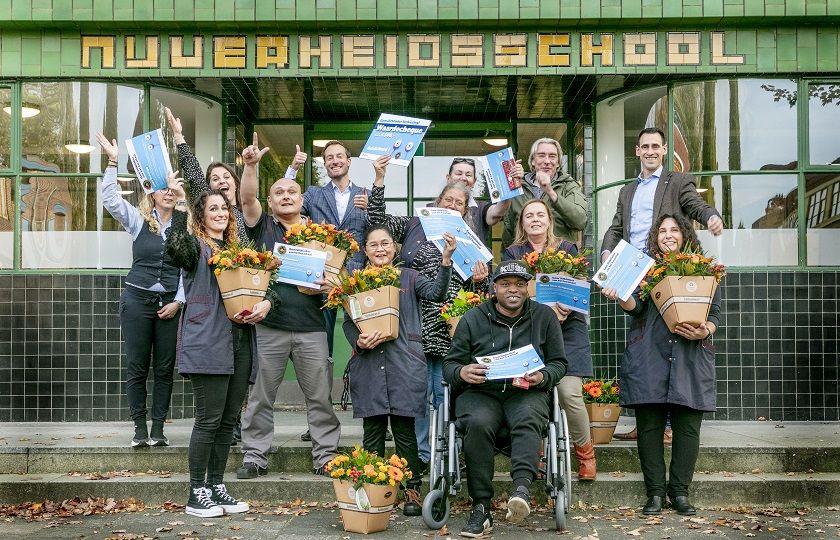 het team Wiebenga van Hanzehogeschool staat voor het pand te juichen met bloemen en hun certificaat